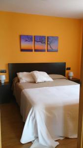 a bedroom with a white bed with three pictures on the wall at Casa El Mirador de Nicolas in La Puebla de Castro