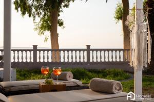 a table with two glasses of wine on a patio at Sandy Suite - seafront & luxury in Chalkida
