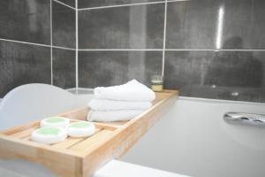 a wooden tray with towels and soap on a bath tub at Luxury 2 Bedroom Northampton Townhouse with Balcony in Northampton +20 photos