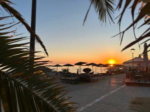a sunset on the beach with chairs and umbrellas at Sea Shell in Nikiti