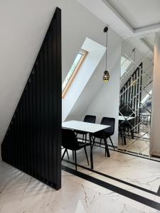 a dining room with a white table and black chairs at Yeti Studio Apartament Krupówki 73C in Zakopane