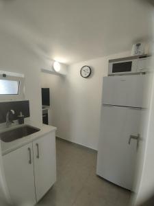 a kitchen with a white refrigerator and a clock on the wall at Casa sintra in São Domingos de Rana
