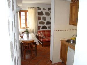 a kitchen with a table and a living room at Casa Rural Paisajes de Tejeda in Tejeda