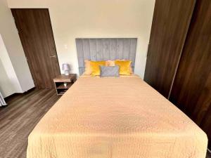 a bedroom with a large bed with yellow pillows at Moderno departamento cercano a Embajada Americana in San Jorge