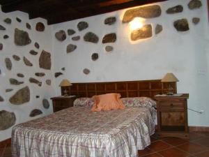 a bedroom with a bed with rocks on the wall at Casa Rural Paisajes de Tejeda in Tejeda