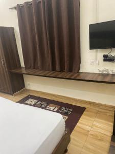 a room with a bed and a curtain and a television at Olive Home Stay in Agra
