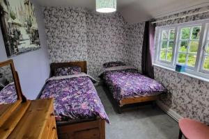 a bedroom with two beds and a window at The Lodge at Fairfield Court in Lickey End