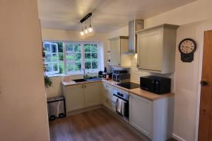 a kitchen with white cabinets and a clock on the wall at The Lodge at Fairfield Court in Lickey End +35 photos