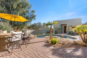 a patio with a table and chairs and an umbrella at The Debonair Derby by PaseoHomesAZ with Heated Pool in Scottsdale