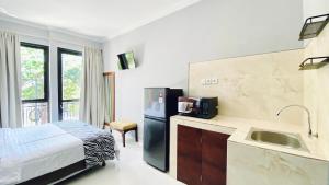 a room with a kitchen with a refrigerator and a sink at Puri Puspa Jimbaran in Jimbaran