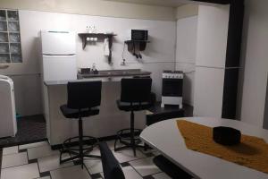 a kitchen with a counter and chairs and a table at Liberdade! Apto no centro! in Caçador