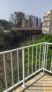 a white railing next to a river with a bridge at Liberdade! Apto no centro! in Caçador