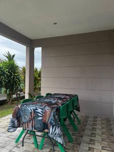 a table with green chairs sitting on a patio at Fare Apetahi - Maison 2 Chambres in Uturoa