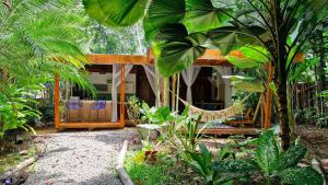 a house with a hammock in the middle of a garden at UP! HOUSE Costa Rica ~ 2 Casitas in Playa Chiquita in Talamanca
