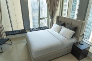 a bedroom with a large white bed with large windows at Downtown Oasis, Burj Khalifa Views, Luxury Amenities in Dubai