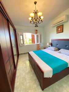 a bedroom with a large bed and a chandelier at فيلا بحمام سباحة مارينا 6 الساحل الشمالي العلمين in El Alamein