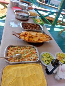 Una mesa con varias bandejas de comida encima. en Casa Toca do Tatu, en Manacapuru