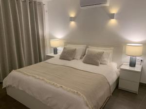 a bedroom with a large white bed with two lamps at Beach Front House 'Casa Neen' in Corralejo