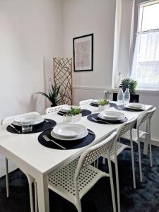 a white table with chairs and plates on it at Grosse Bequeme Wohnung in Recklinghausen