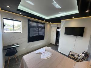 a bedroom with a bed and a flat screen tv at Suíte Silver 201 com ar condicionado in Santo Antônio do Descoberto