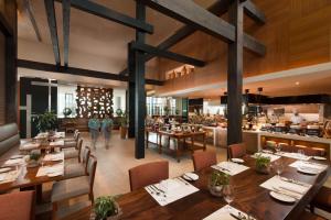 un ristorante con tavoli e sedie in legno e una cucina di Conrad Manila a Manila Altre 37 foto