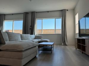 a living room with a couch and two windows at Spacious new house in Folsom Ranch 4BD and 3BA with backyard and BBQ grill in Folsom