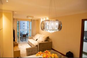 a living room with a couch and a chandelier at Apartamento Beira Mar em Praia de Itaparica - Vila Velha- ES in Itaparica