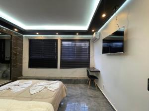 a bedroom with a bed and a desk and windows at Suíte Silver com sofa cama in Santo Antônio do Descoberto