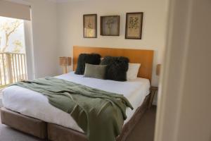 a bedroom with a bed with a green blanket on it at Villa 3br Tempranillo Villa located within Cypress Lakes Resort in Pokolbin +27 photos