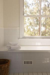 a white bathroom with a window and towels on a shelf at Villa 3br Tempranillo Villa located within Cypress Lakes Resort in Pokolbin