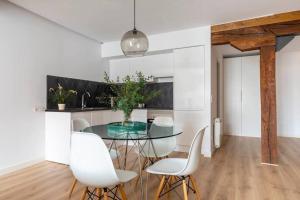 a dining room with a glass table and white chairs at Piso moderno en el centro detrás del edificio Banco Santander in Santander +14 photos