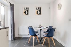 Un comedor con una mesa y sillas azules. en Luxury Ashford Home in secure neighbourhood with Free Parking, en Ashford