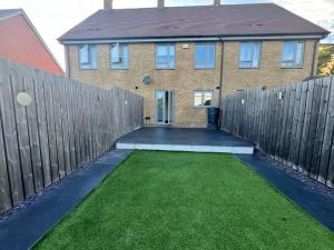 una casa con una valla y un patio con hierba en Luxury Ashford Home in secure neighbourhood with Free Parking, en Ashford