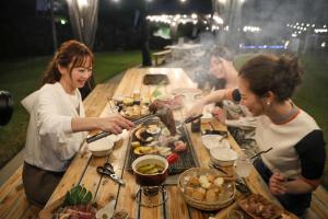 MatsuuraGlamping village Seagrand的一群人围坐在桌旁，吃着食物