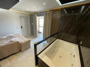 a bathroom with a tub and a bed in a room at Suíte Gold com varanda e Hidro 302 in Santo Antônio do Descoberto