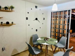 a dining room with a table and a clock on the wall at Casa B Héroes León in San Carlos