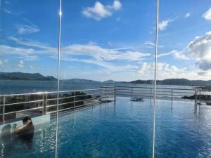 a man sitting in a swimming pool next to a body of water at Langkawi Simfoni Cassia Suite 09 9 Pax in Kuah