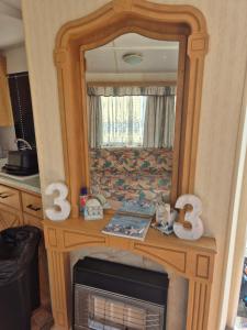 a wooden table with a mirror and a fireplace at Sandgate retreat hemsby 2023 in Hemsby