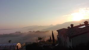a misty sunrise with a house and mountains in the background at Villa Colticciola Agriturismo Marche in Cagli
