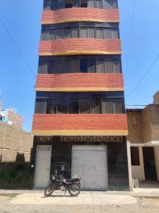 a motorcycle parked in front of a tall building at Thiago MG in Chiclayo