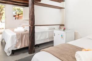 a bedroom with two beds and a refrigerator at Pousada da Praça Caraíva in Caraíva +67 photos