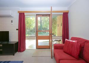 a living room with a red couch and a sliding glass door at Cedar Holiday Units - Apartment 2 in Bright