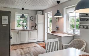 a kitchen with white cabinets and windows and a table at Amazing Home In Skagen With Wifi in Skagen