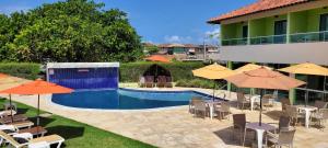 a swimming pool with chairs and umbrellas and a building at Pousada Solar Dos Carneiros in Praia dos Carneiros