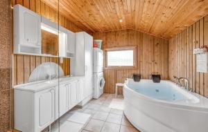 a bathroom with a tub and a washer and dryer at Holiday Home Hvide Sande With A Patio 04 in Bjerregård