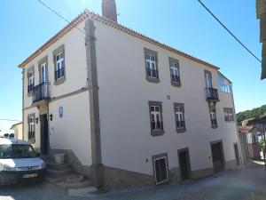 a white building with a car parked in front of it at Cruzeiro - Guest House in Vale de Porco