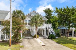 a white house with a porch and palm trees at Beach House with Pool - North Myrtle Beach in Myrtle Beach