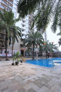a swimming pool with palm trees in front of a building at Nusantara Rooms Mutiara By Reccoma in Bekasi