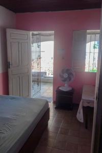 a bedroom with pink walls and a bed and a fan at Hostel Residence Girassol in Belém