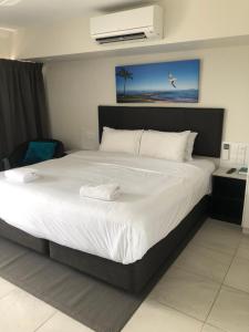 a bedroom with a large bed with white sheets at Superior Studio 20 Endeavour Inn in Emu Park